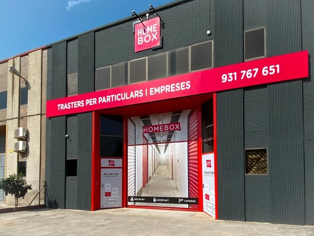 Dark grey warehouse entrance with red HOMEBOX sign and corridor view at HOMEBOX Gavà - Castelldefels, Carrer dels Oficis, 13, Gavà