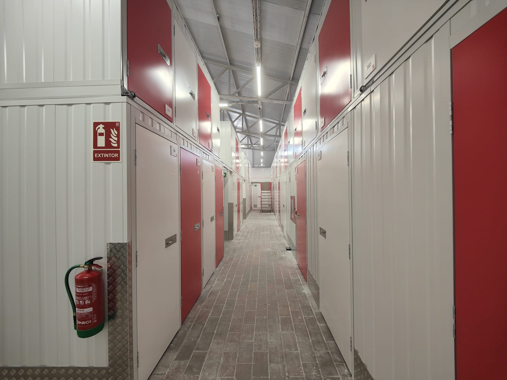 Couloir intérieur du centre HOMEBOX Barcelona - Sant Andreu avec portes de box rouges et blanches.