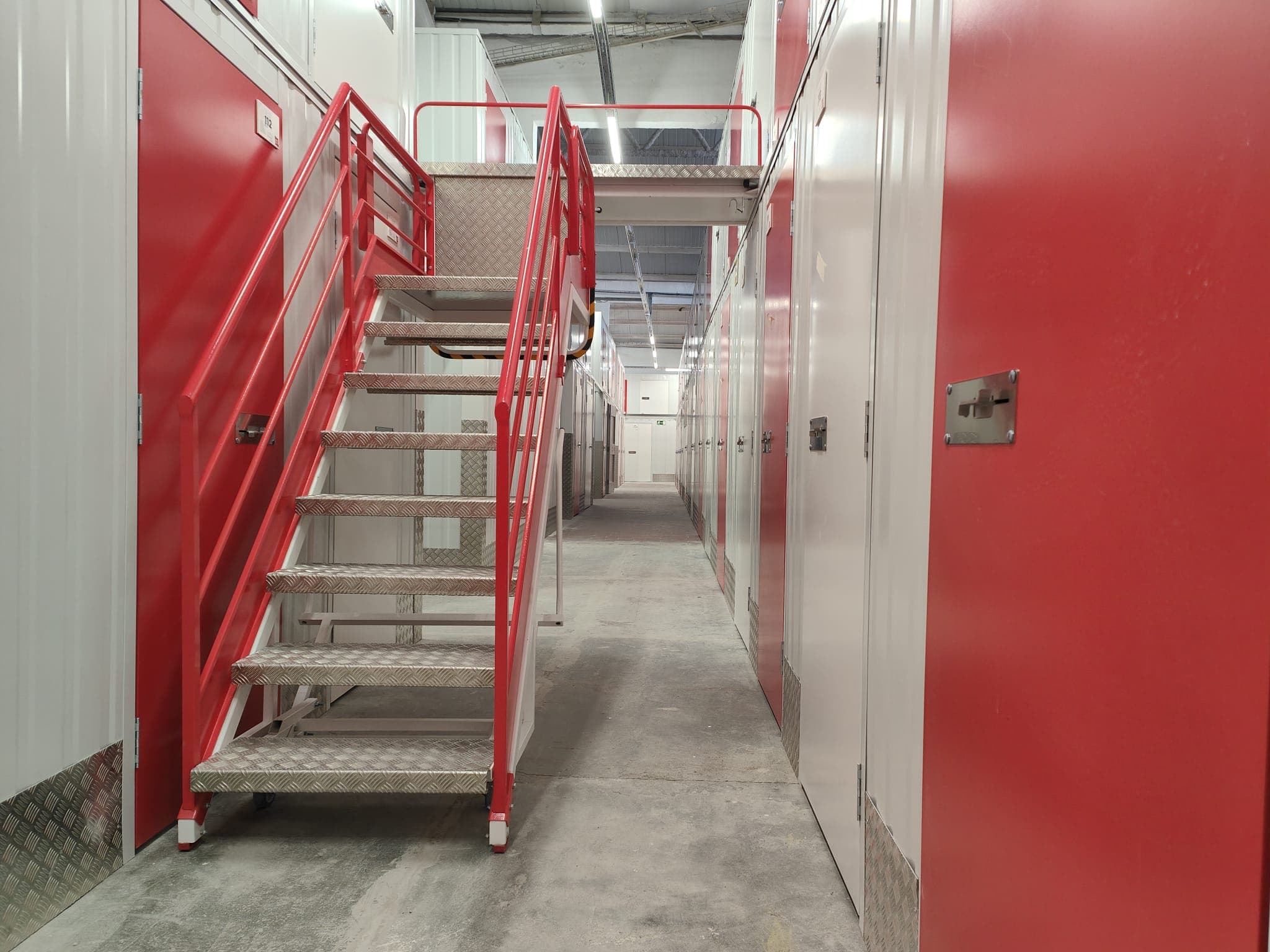 Escalier métallique rouge menant à l’étage du centre HOMEBOX Barcelona - Sant Andreu.