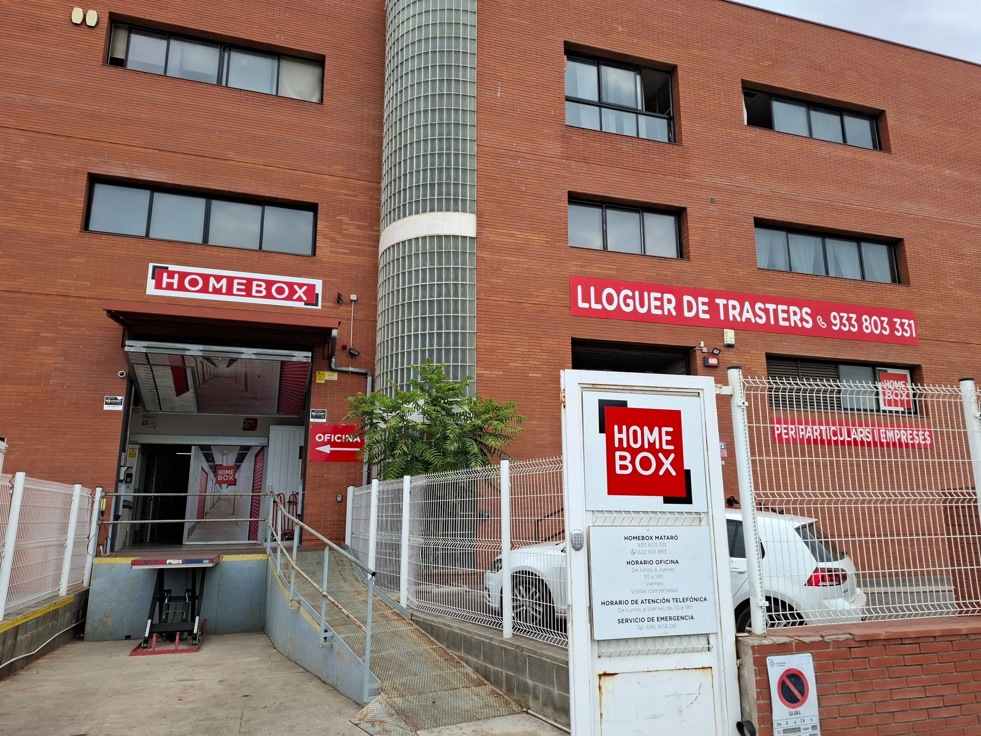 Entrada de l'edifici de maó vermell amb rètol HOMEBOX i cartell de lloguer de trasters del centre HOMEBOX Mataró, Carrer Josep Calvet 28, Mataró